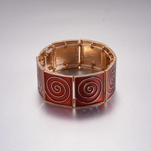 Close-up of red enamel spiral patterns on a golden elastic geometric square bracelet