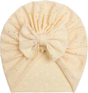 Detail of baby turban hat in cream yellow with hollow embroidery and large bow decoration