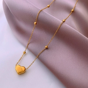 Elegant gold heart pendant necklace with beaded ball chain on lavender silk fabric