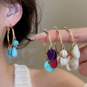 Detail view of ethnic hoop earrings with stone tassels and natural shell pendants
