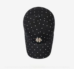 Detailed top view of a black washed cotton baseball cap with white polka dots and gold embroidery