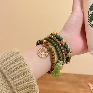 Detail of bohemian multilayer sandalwood beaded bracelet with tree of life charm and tassel