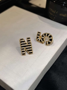 Macro detail of asymmetric gold-plated N and 5 earrings with zircon and black stripes