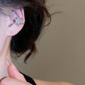 Close-up of a floral ear cuff featuring clear zircons and silver flower petals on the ear