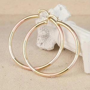 Driekleurige oorringen met goud, roségoud en zilveren segmenten op minimalistisch display