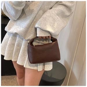 Détail du mini sac carré marron avec motif rich rabbit embossé tenu par un mannequin