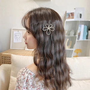 Detail showing elegant metal flower hair clip with rhinestones worn by a model