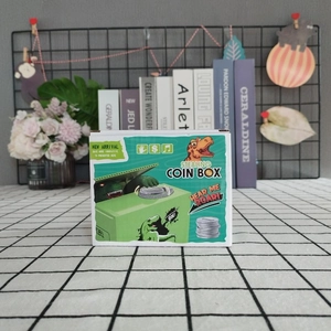 Detail of green dinosaur stealing coin box in innovative packaging on a plaid surface