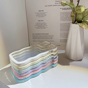 Stack of colorful wavy border iPhone cases in various macaron shades on a desk