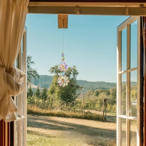 Detail of crystal flower suncatcher hanging by a window with scenic outdoor background