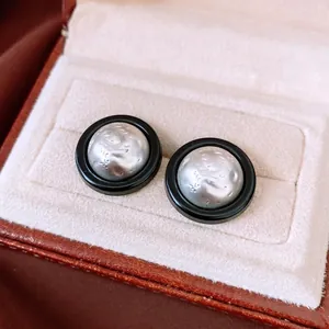 Retro round earrings with black enamel and silver textured dome in a leather jewelry box