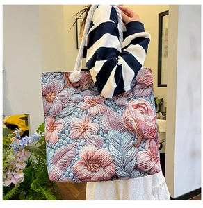 Detailed close-up of ethnic floral embroidery on a large canvas tote bag with rope straps