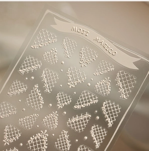 Detailed macro view of 5D white lace relief nail stickers with grid floral patterns