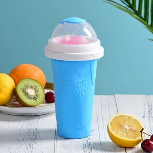 Blue Frozen Magic silicone slushy maker cup with pink smoothie on white wooden table