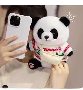 Detail eines süßen Pandabär-Plüschtiers mit festlichem Weihnachtspullover und Umhängetasche