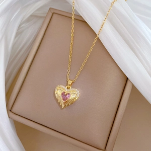Pink heart pendant necklace with golden wings and zircon stones on jewelry box