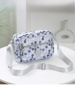 Close-up of multi-layer zipper pockets and adjustable strap on a blue polka dot nylon bag