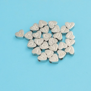 Vue macro de perles alphabet en forme de cœur en argent pour bijoux DIY sur fond bleu