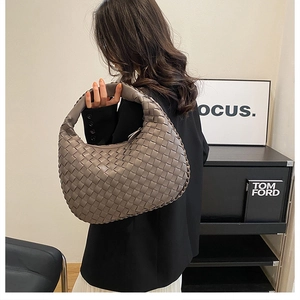 Detailed view of the greige woven hobo bag showing texture and crescent shape on a model