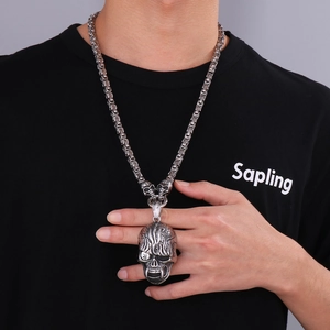 Close-up of punk style skull pendant on a heavy stainless steel chain worn by a male model