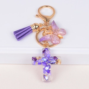 Detail of cross keychain with purple tassels, butterfly pendant and gold foil resin