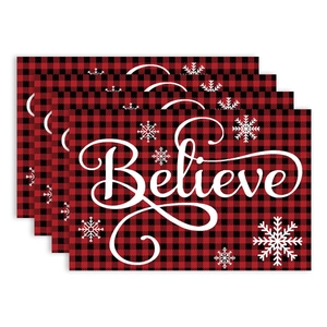 Set of four red and black plaid Christmas placemats with Believe text and snowflakes