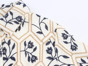 Detailaufnahme der Stickerei auf dem beigen Vintage-Hemd mit blauen Blumenmustern