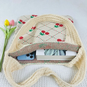 Detail shot of beige cherry knit tote bag showing interior capacity with phone and book