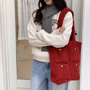 Detail of red wool felt tote bag showing four patterned front pockets and soft texture