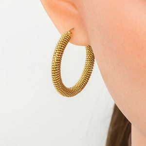 Close-up of golden hoop earrings with spiral texture shown on model in side profile view