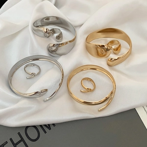 Polished oval open bracelet and ring set on white silk fabric with luxury metal finish
