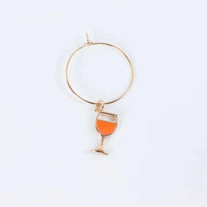 Close-up of golden ring loop with an orange enamel wine glass pendant for party identification