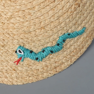 Makrodetail aus natürlichem Bast mit blauer Schlangenstickerei und roter Zunge
