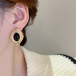 Close-up of vintage oval black stone earrings with gold-toned textured metal frame