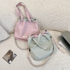Flat lay of pink and green canvas tote bags with drawstring closure on plush background