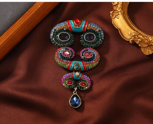 Detail of vintage palace style brooch with colorful rhinestones and blue teardrop gem