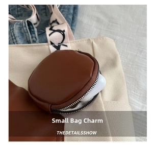 Close-up of brown PU leather mini pouch charm attached to a canvas tote bag