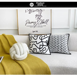 Detail of woven velvet knot cushion and abstract pillows on a modern sofa setup