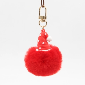 Close-up of red plush pompom keychain with a polka dot Christmas hat and gold metal clasp