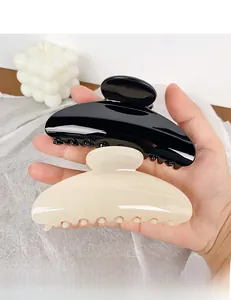 Detail of large semi-round hair claws in black and cream beige with glossy finish