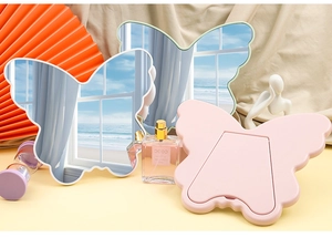 Detailed view of butterfly-shaped makeup mirrors in white, green and pink with stands