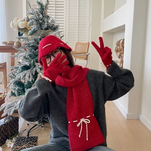 Detail of red knitted winter set with white bow accents including scarf and hat