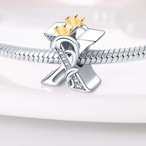 Close-up of letter X charm with gold crowns and cubic zirconia on a snake chain