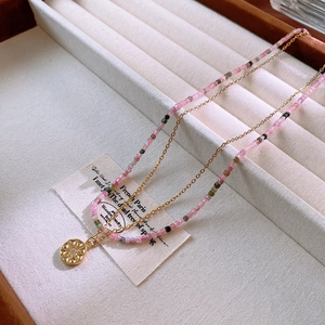 Detail of layered gold star pendant and colorful natural stone beaded necklace on jewelry box