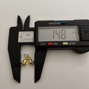 Golden double bell pendant with 14.8mm width measurement on digital caliper