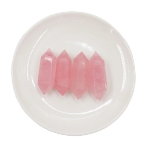 Polished natural pink rose quartz double point crystal pillars on a white plate