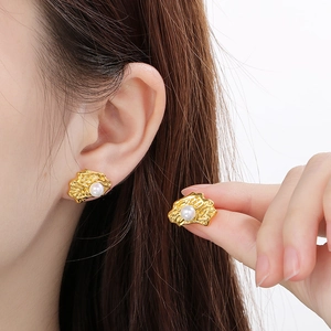 Irregular textured gold pearl stud earrings worn by a model in a minimalist style