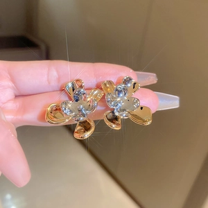 Detailed view of golden 3D flower earrings with high-gloss finish and starburst light effect