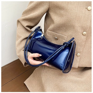 Detail of a navy blue glossy patent leather hobo bag with a gold zipper on a model