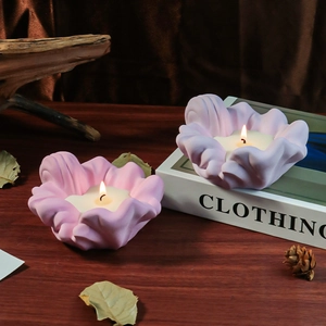 Close-up of purple petal shaped scented candles on dark wooden table with winter decor